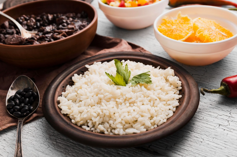 Imagem mostra comida na mesa separada em cada recipiente: arroz, feijão, salada e fruta